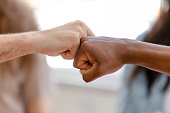Diverse male hands giving fist bump, close up view