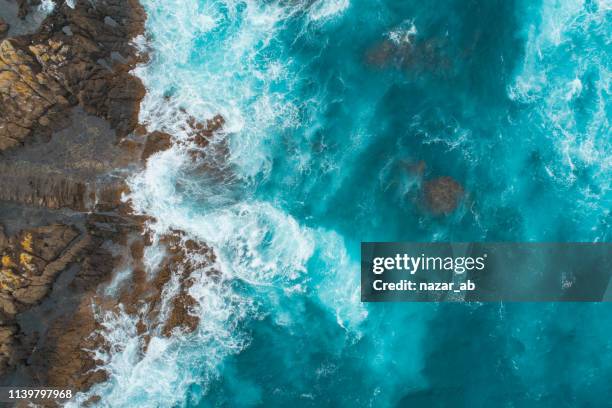aerial view of waves splashing on beach. - rocky landscapes stock pictures, royalty-free photos & images