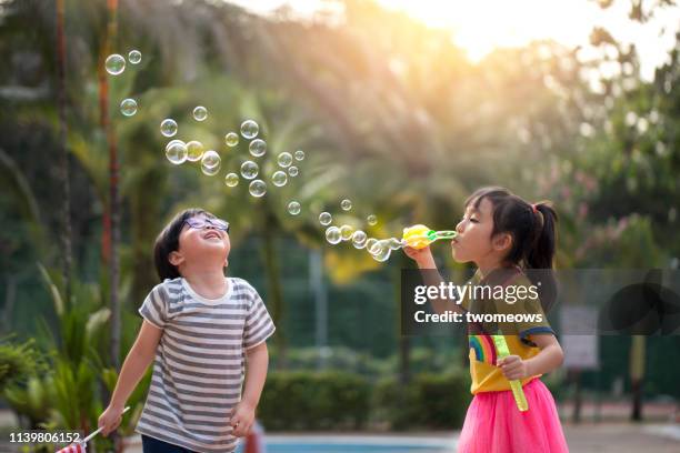 preschoolers boy and girl soap bubble play time. - blowing bubbles foto e immagini stock