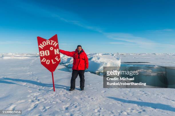 man standing by sign at north pole, arctic - nordpol stock-fotos und bilder