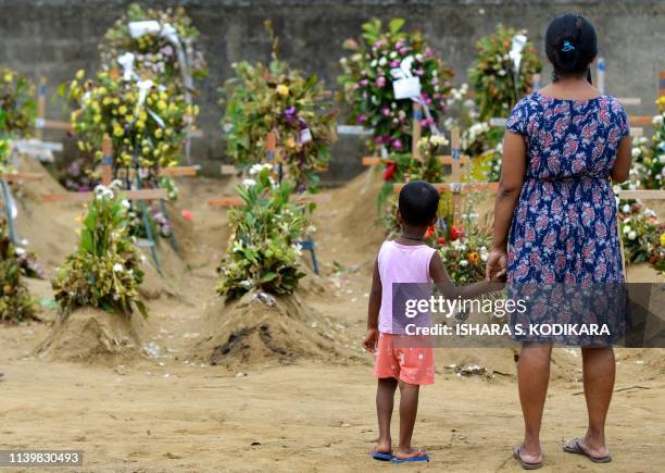 Relatives pay their respects in front of the graves of the victims of recent bomb blasts at St. Sebastian's Church in Negombo on April 28 a week...