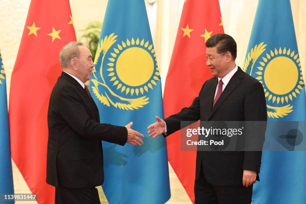 Kazakhstan's Former President Nursultan Nazarbayev, left, take a step to shake hands with China's President Xi Jinping before a meeting at the Great...