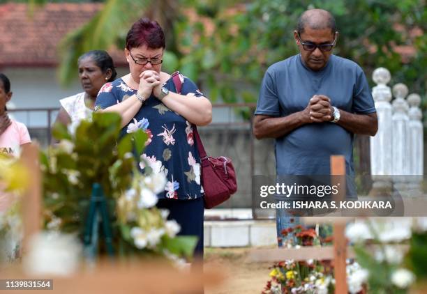 Relatives pay their respects in front of the graves of the victims of recent bomb blasts at St. Sebastian's Church in Negombo on April 28 a week...
