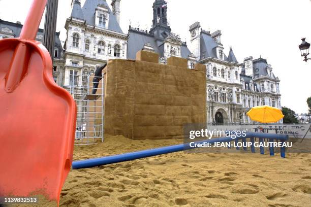 Un homme installe un château de carton, le 03 août 2001 devant la mairie de Paris, sur un bac à sable géant dont le sable a été transporté de Pornic...