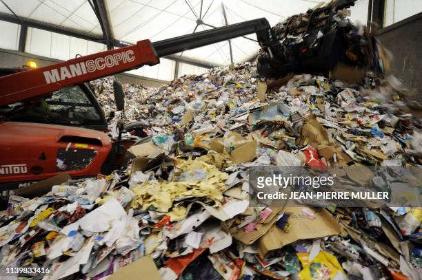 Un véhicule à godet entasse des journaux et des magazines au centre de traitement des déchets recyclables de la sociéte Astria, le 1er octobre 2008 à...