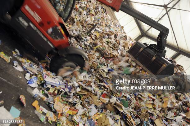 Un véhicule à godet entasse des journaux et des magazines au centre de traitement des déchets recyclables de la sociéte Astria, le 1er octobre 2008 à...