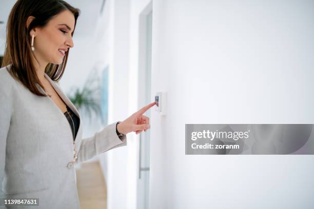 businesswoman with finger on light switch - turning on or off stock pictures, royalty-free photos & images