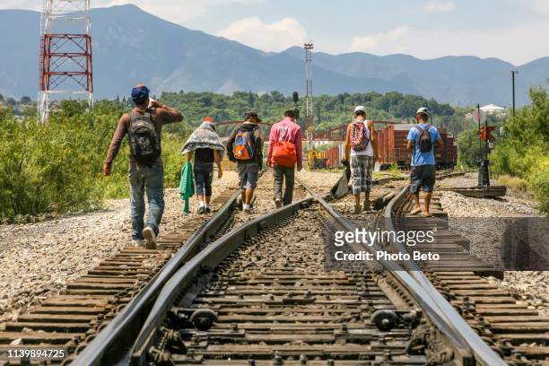 a group of migrants walk along the railroad near the us-mexico border in the state of coahuila in northern mexico - emigration and immigration stock pictures, royalty-free photos & images