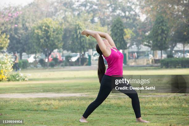 belle femme pratiquant le yoga sur le champ herbeux au parc - salutation au soleil photos et images de collection