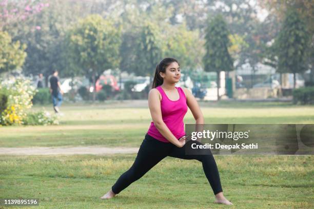 hermosa mujer practicando yoga en grassy field en park - girls in bras photos fotografías e imágenes de stock