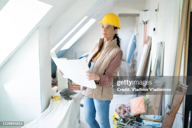 female architect looking at blueprints on construction site - attic conversion stock pictures, royalty-free photos & images