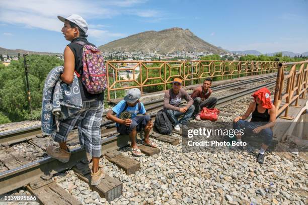 a group of migrants rest along the railroad near the us-mexico border in the state of coahuila in northern mexico - immigrants crossing sign stock pictures, royalty-free photos & images
