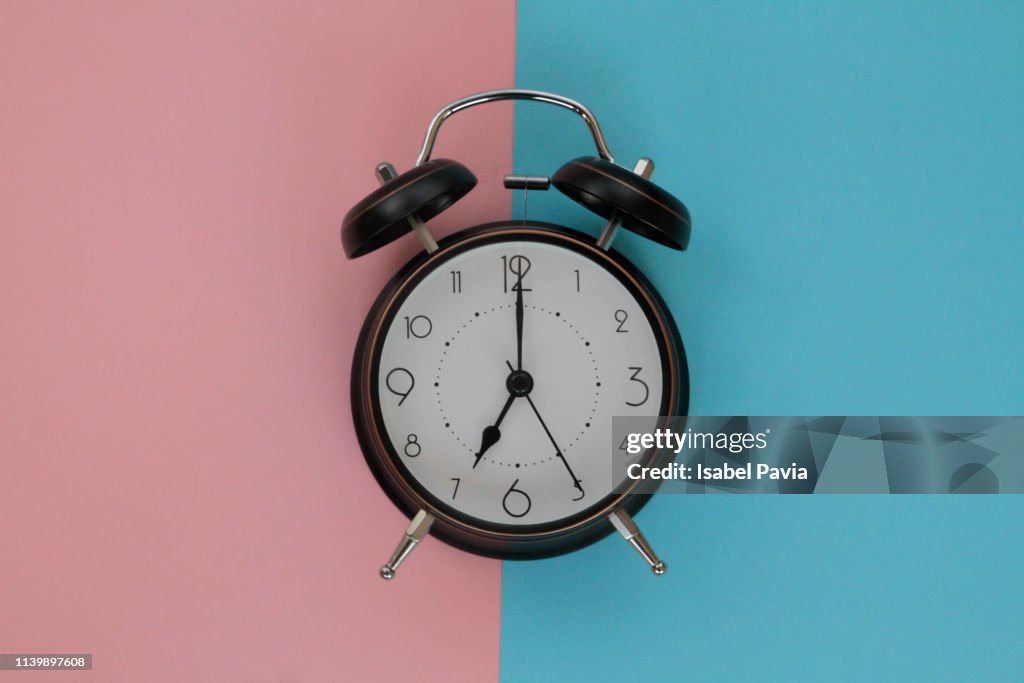 Vintage alarm clock on pink and blue background