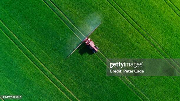tractor spraying field - insecticida fotografías e imágenes de stock