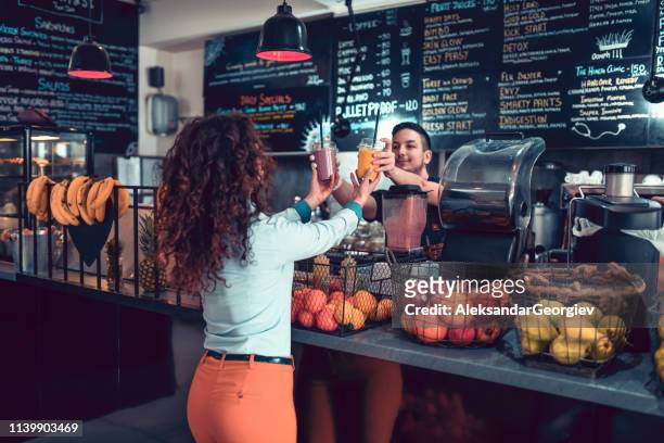 modern female taking smoothies from barista - barista coffee restaurant stock pictures, royalty-free photos & images