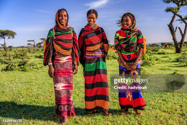 junge afrikanische frauen, die wasser aus dem brunnen, äthiopien, afrika transportieren - african village stock-fotos und bilder