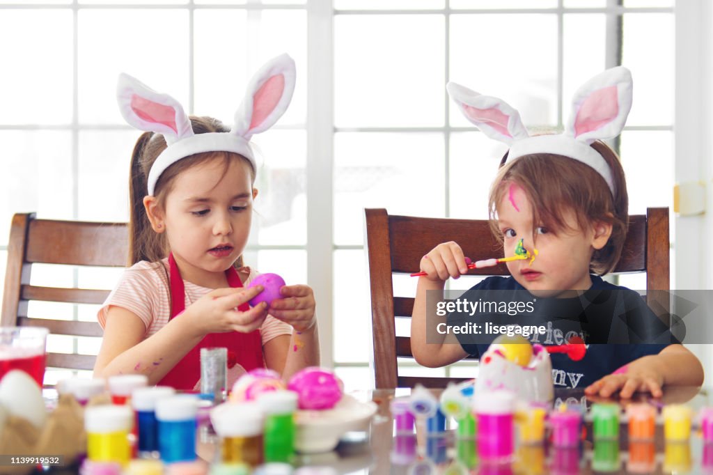 Sister and brother painting Easter eggs