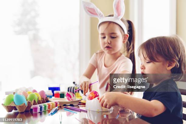 sister and brother painting easter eggs - dirty easter stock pictures, royalty-free photos & images