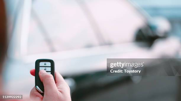 man's hand presses on the remote control car alarm systems. - car alarm stock-fotos und bilder