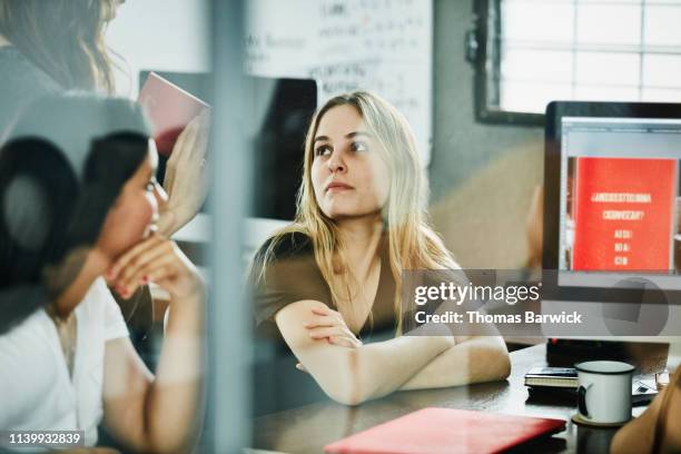 businesswoman listening to colleague present project ideas during meeting in studio - 設計室 個照片及圖片檔