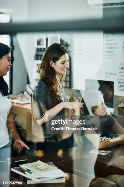 smiling businesswoman in discussion with coworkers during meeting in design studio - intelligence community stock pictures, royalty-free photos & images