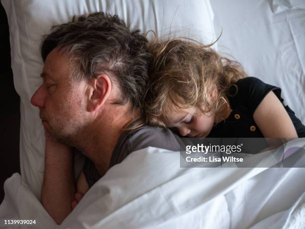 father and daughter cuddling in bed - sleeping and bed stock pictures, royalty-free photos & images