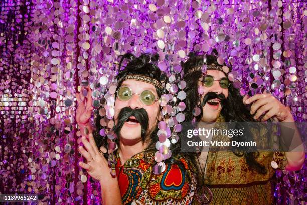 two men in hippie costumes with false mustaches - disco costume stock pictures, royalty-free photos & images