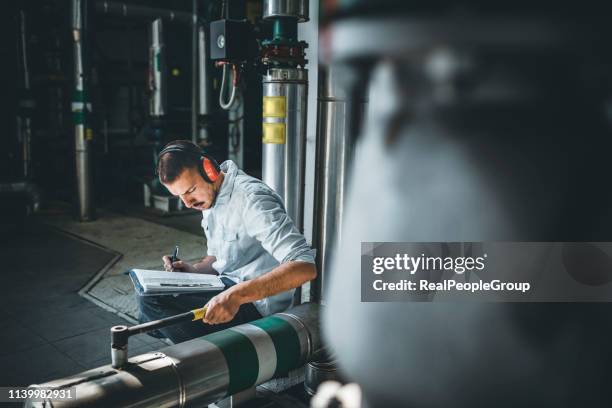 young technician is inspecting heating system in boiler room - gas turbine stock pictures, royalty-free photos & images