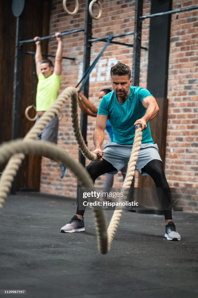 Strong latin american man battle rope training at the gym