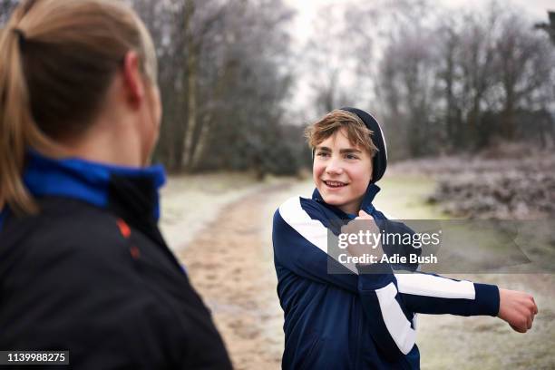 teenage boy stretching arm, looking at mother smiling - bush live stockfoto's en -beelden