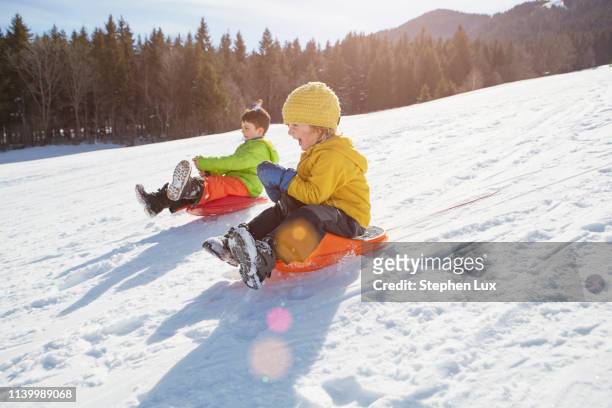 boys tobogganing - snow fun stock pictures, royalty-free photos & images
