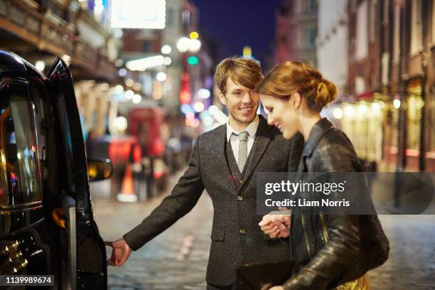 couple getting into taxi cab, london, england - caballerosidad fotografías e imágenes de stock