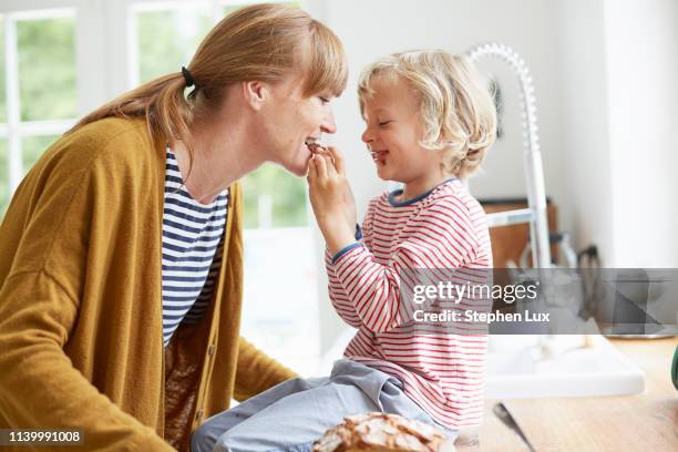 young boy feeding mother a sweet treat - mother and child snacking stockfoto's en -beelden