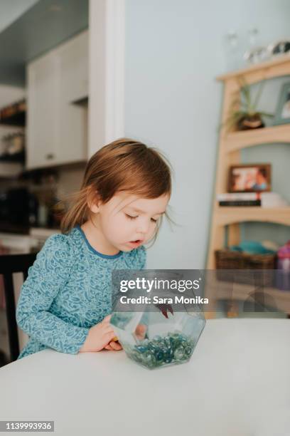 female toddler peering at goldfish bowl on table - goldfish bowl stock pictures, royalty-free photos & images