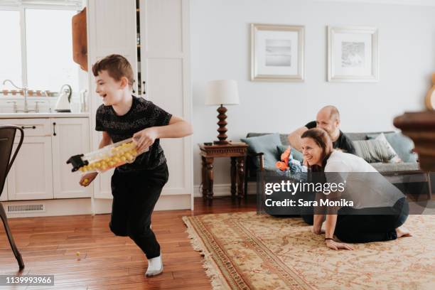 boy running away from father with foam ball gun at home - arma de brinquedo imagens e fotografias de stock