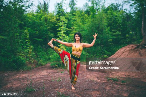 woman doing standing big toe pose in forest - harem pants imagens e fotografias de stock