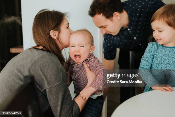 mid adult couple with toddler daughter and crying baby son in living room - één ouder stockfoto's en -beelden