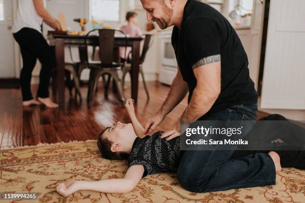 father and son wrestling on carpet at home - girl wrestling stock pictures, royalty-free photos & images