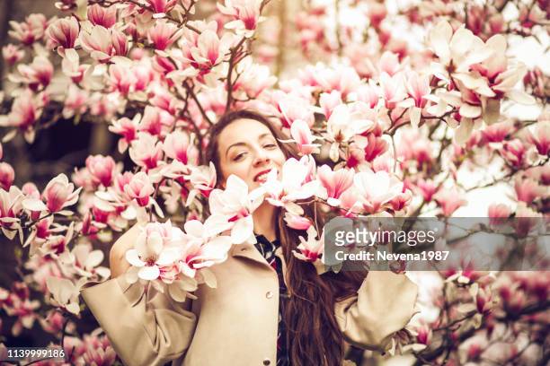 happy woman enjoying spring sun under a magnolia - magnolia stellata stock pictures, royalty-free photos & images