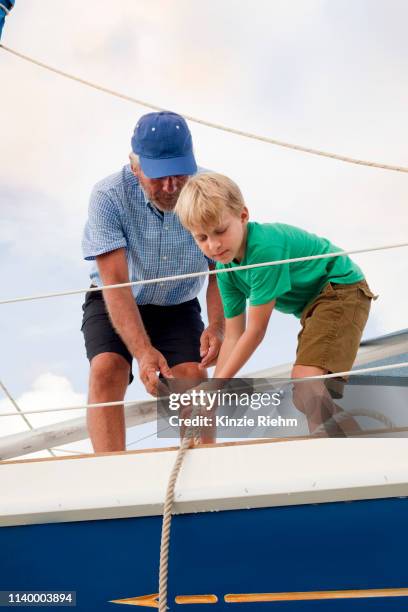 boy helping grandfather pull ropes on sailboat - kid sailing imagens e fotografias de stock