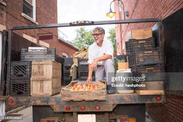 farmer unloading crates of organic tomatoes outside grocery store - heshphoto - fotografias e filmes do acervo