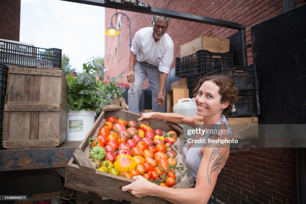 Farmers unloading crates of organic tomatoes outside grocery store