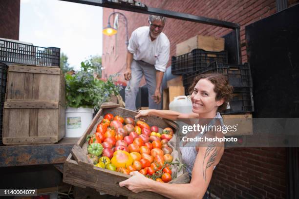 farmers unloading crates of organic tomatoes outside grocery store - heshphoto - fotografias e filmes do acervo