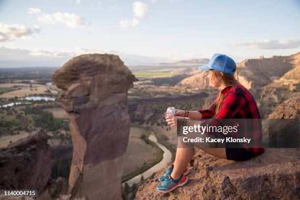 young woman sitting gazing at view from top of smith rock, oregon, usa - smith rock state park stock-fotos und bilder