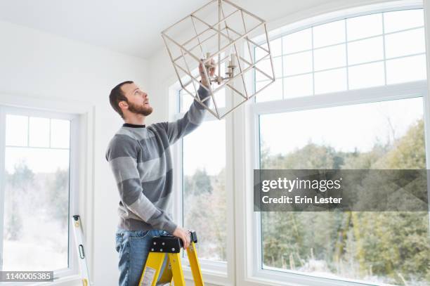 young man installing ceiling light - step stool stock pictures, royalty-free photos & images