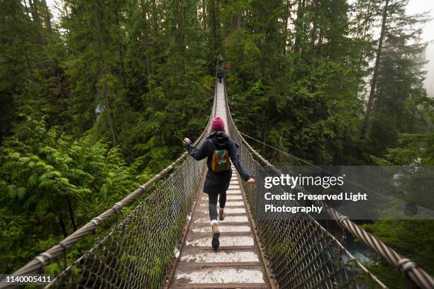 woman on lynn canyon suspension bridge, north vancouver, british columbia, canada - touwbrug stockfoto's en -beelden