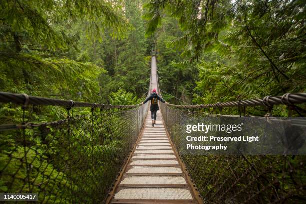 woman on lynn canyon suspension bridge, north vancouver, british columbia, canada - vancouver kanada stock-fotos und bilder