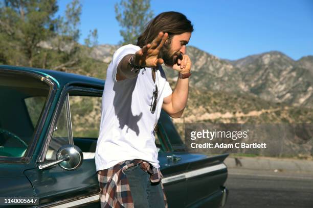 young man talking on smartphone at roadside, los angeles, california, usa - california road trip stock pictures, royalty-free photos & images