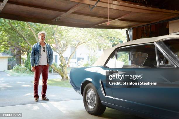 young man staring into garage at vintage car - auto garage foto e immagini stock
