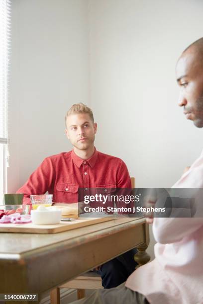 homosexual couple sitting at dining table arguing - lunch argument ストックフォトと画像
